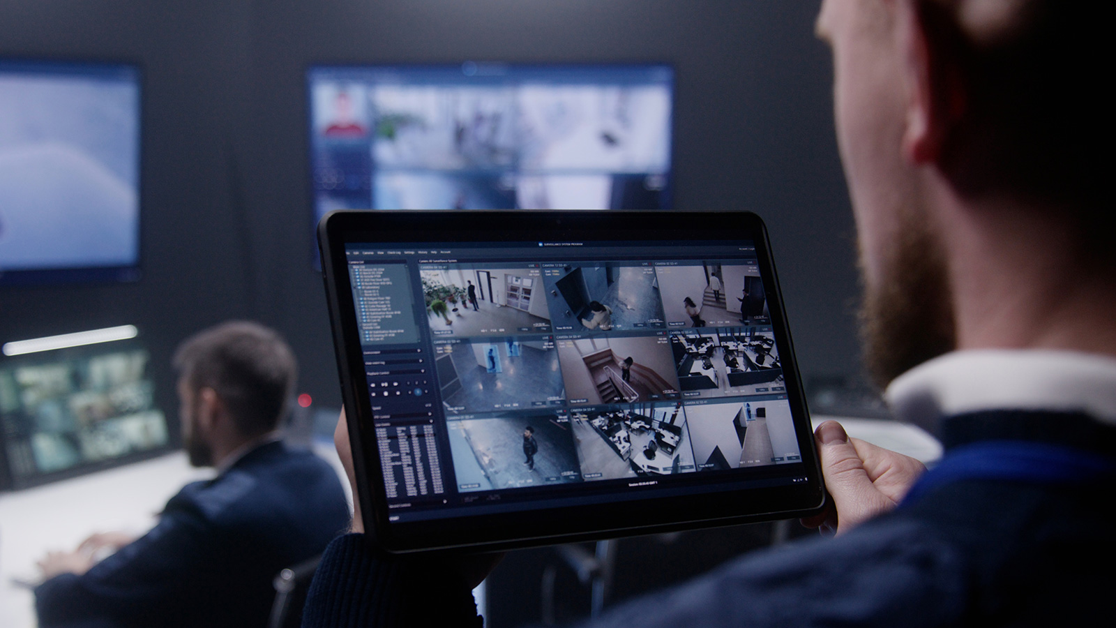 A security manager sitting in front of multiple computer screens with various screenshots of a building.
